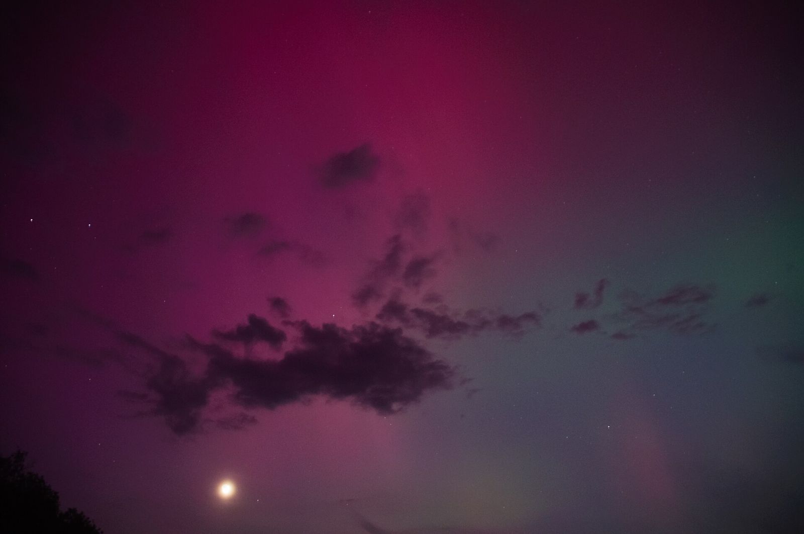 A magenta aurora glow with the Moon low over the horizon