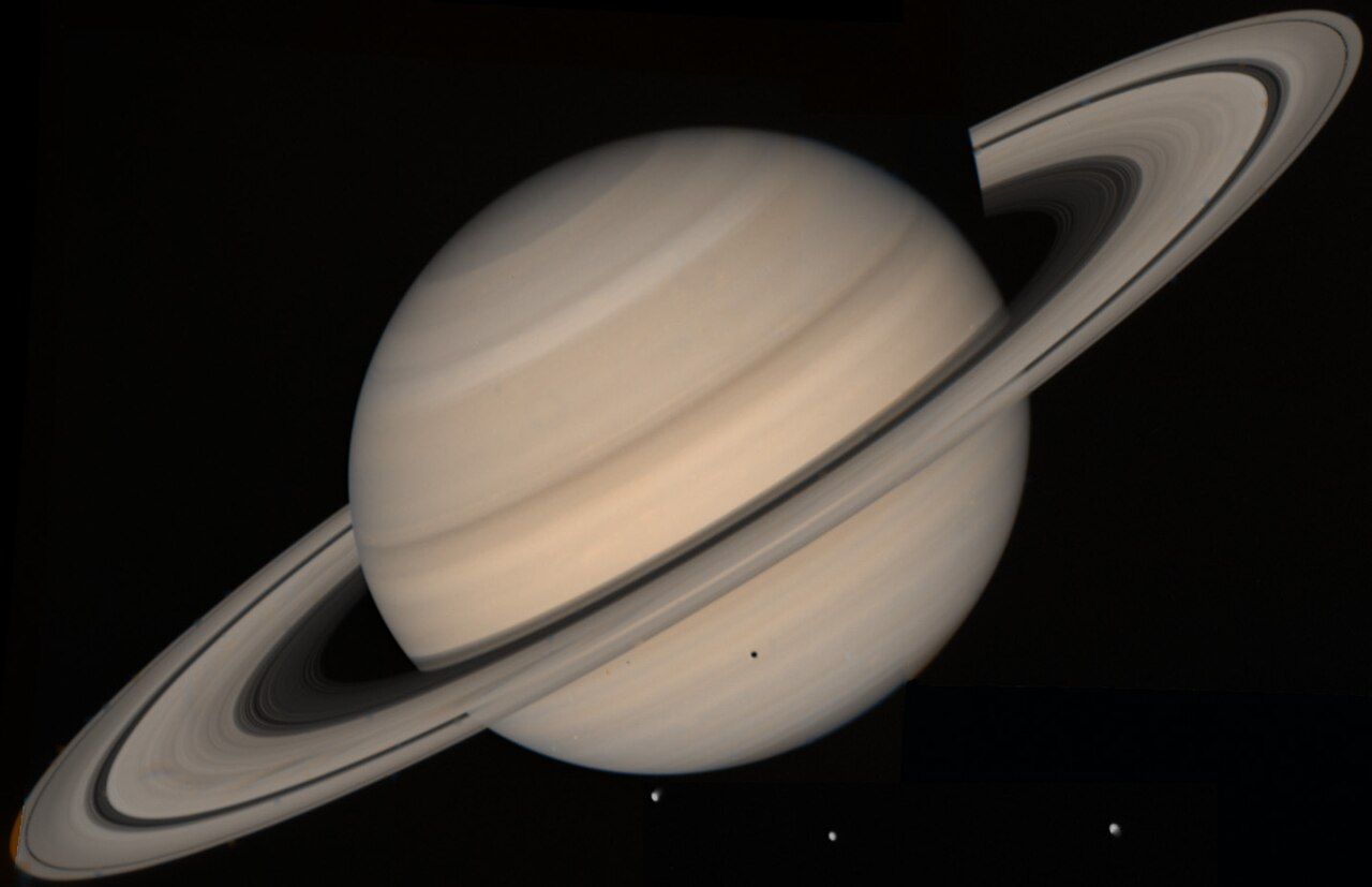 Saturn with its wide rings and three moons